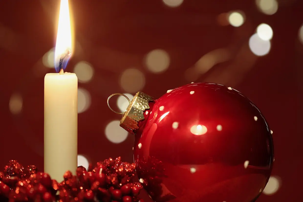 Une bougie près d'une boule de noel, représentant les risques d'incendies dus aux décorations de noel